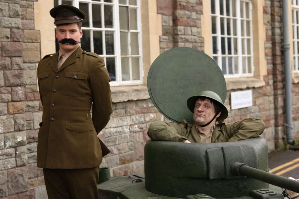 Two Performers pose in a tiny replica ww2 tank