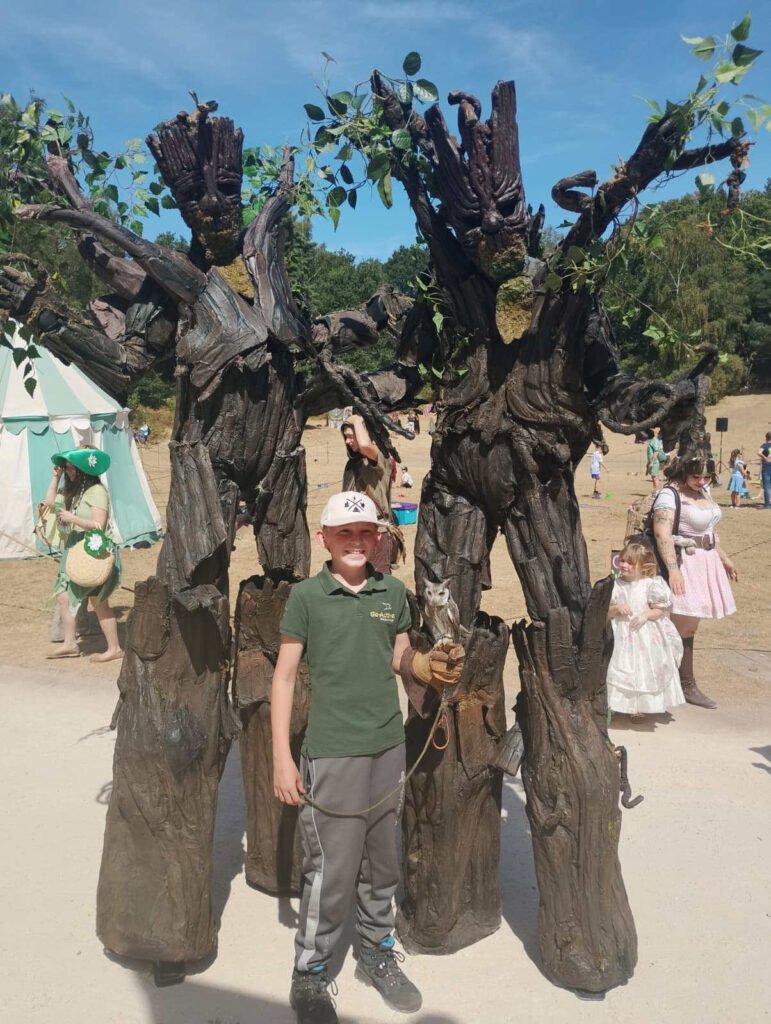 Megabeast's tree stilt walkers with a young man holding a real owl.