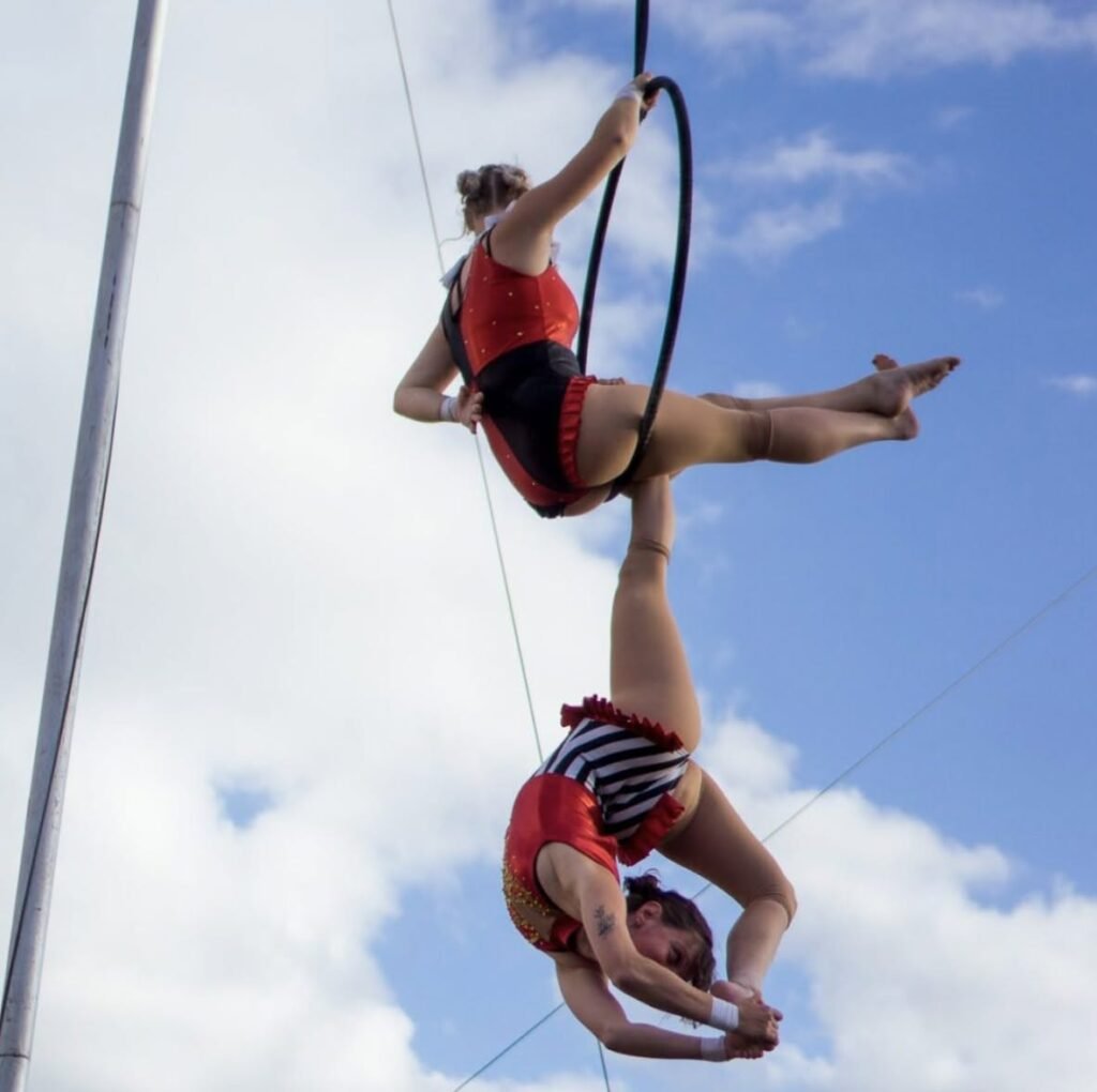 Two circus artists hanging from an aerial hoop in an acrobatic pose